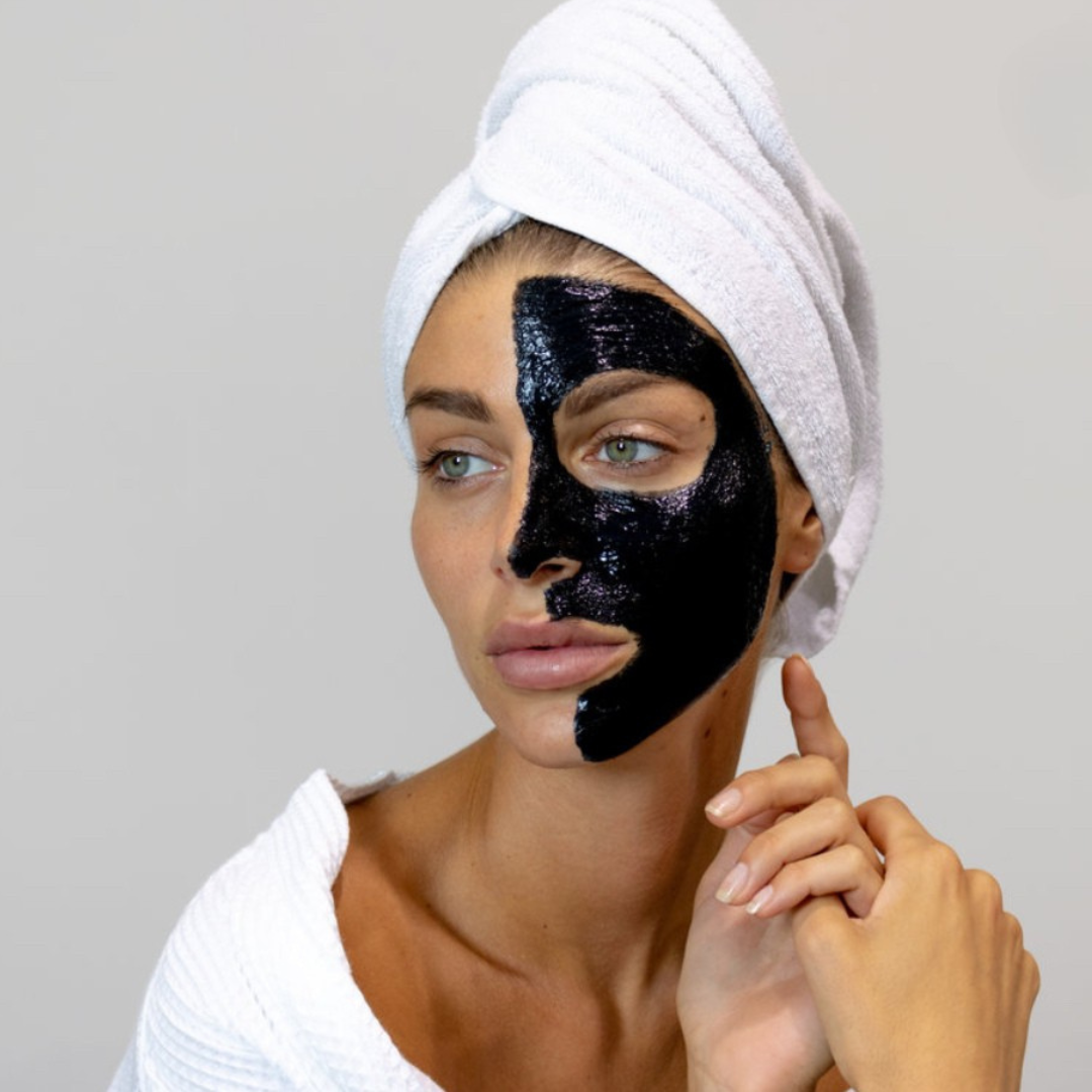Femme appliquant le masque Peeling V Carbon sur la moitié de son visage. Soin exfoliant idéal pour purifier et illuminer la peau.