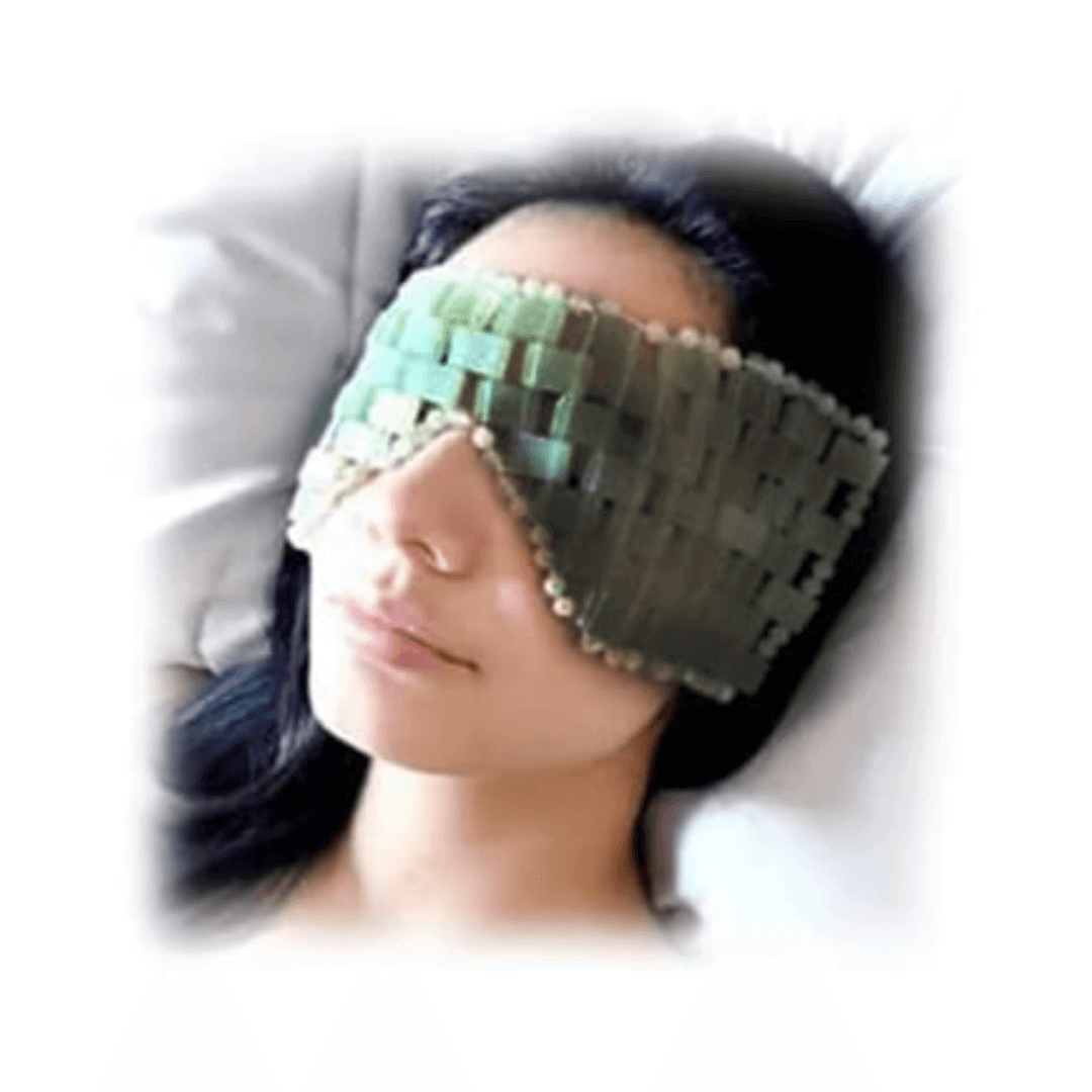 Femme allongée portant un masque relaxant en pierres de jade, idéal pour détendre et améliorer l'élasticité du contour des yeux.