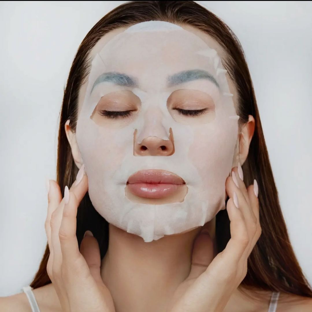 Femme appliquant le Masque Tissu Professionnel Niacinamide, +Maskology pour un soin du visage hydratant et équilibrant en 15 minutes.