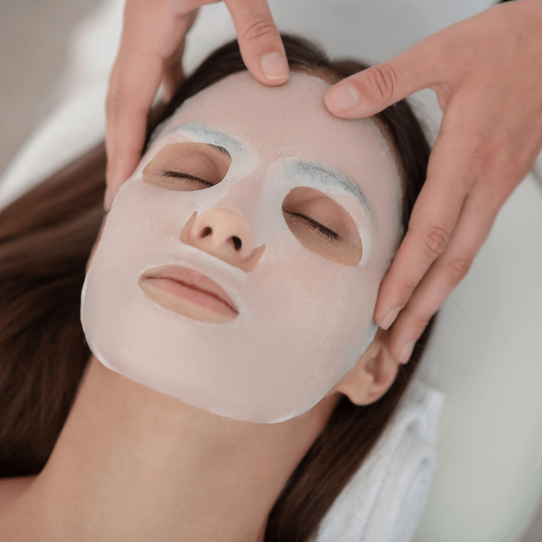 Femme recevant un soin du visage avec un masque, mettant en valeur le Kit Complet Microneedling.
