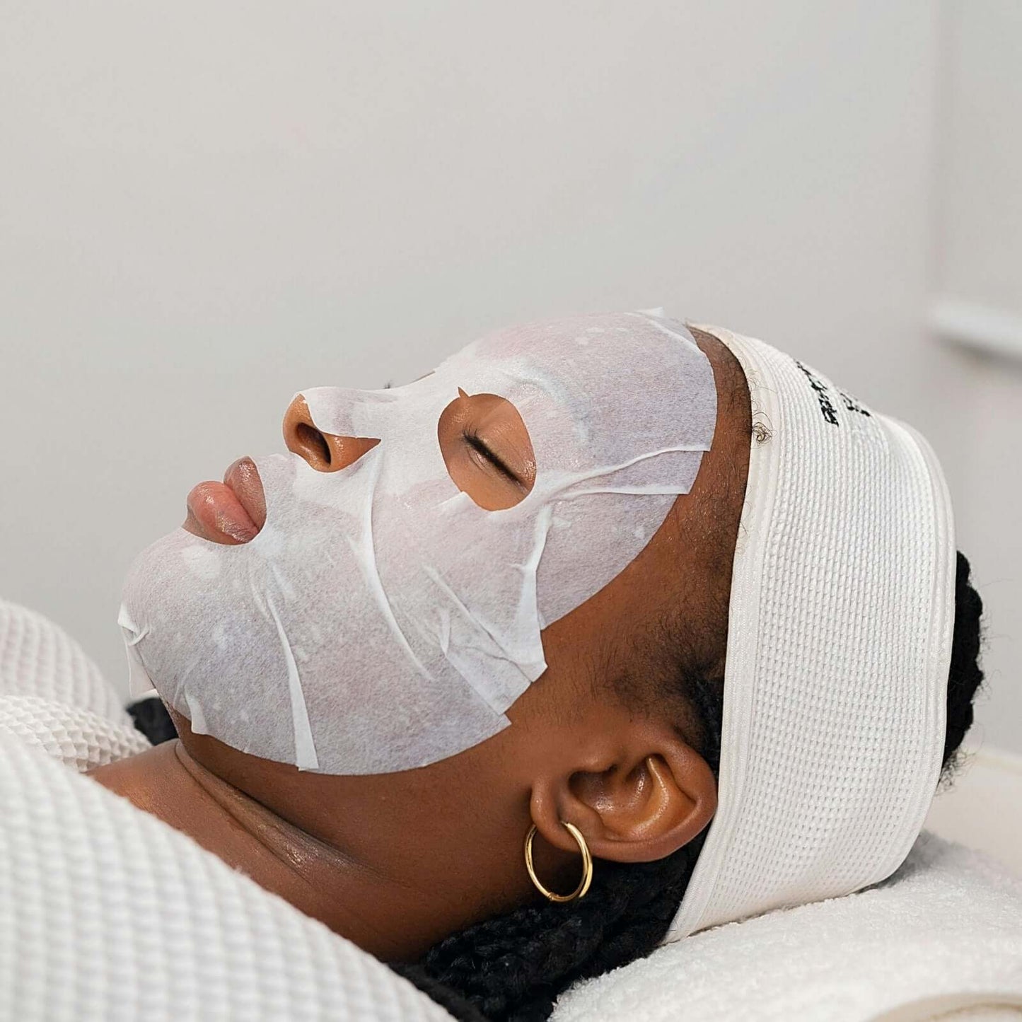 Femme appliquant un Masque Acide Hyaluronique sur son visage pendant un soin de beauté.