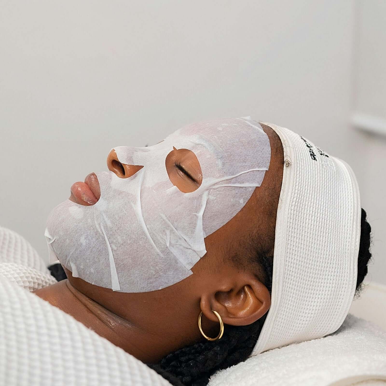Femme appliquant un Masque Acide Hyaluronique sur son visage pendant un soin de beauté.