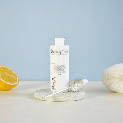 Peeling PHA 25 BeautyMed bottle with dropper on a stone surface next to lemon and towel.